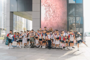 the speakers taking photo with the student reporters in front of the installation